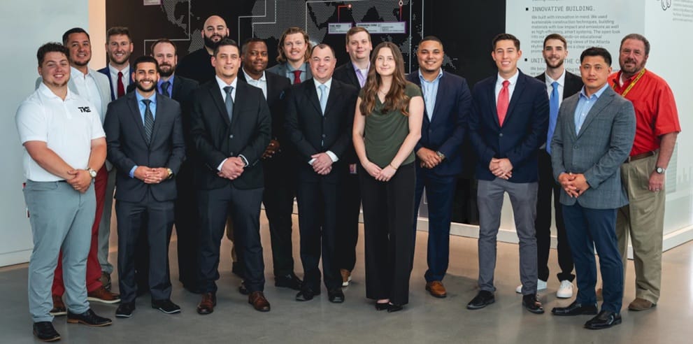 Un grupo de participantes de STEP con ropa formal posa para una foto en una oficina de TKE.